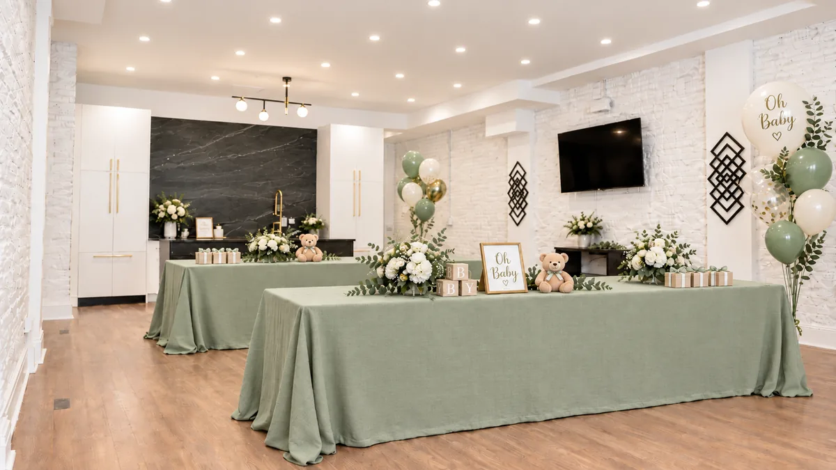 Example baby shower setup at 3535 Venue in Humboldt Park: long tables with sage tablecloths, white flowers, teddy bears and Oh Baby balloons (virtually staged)