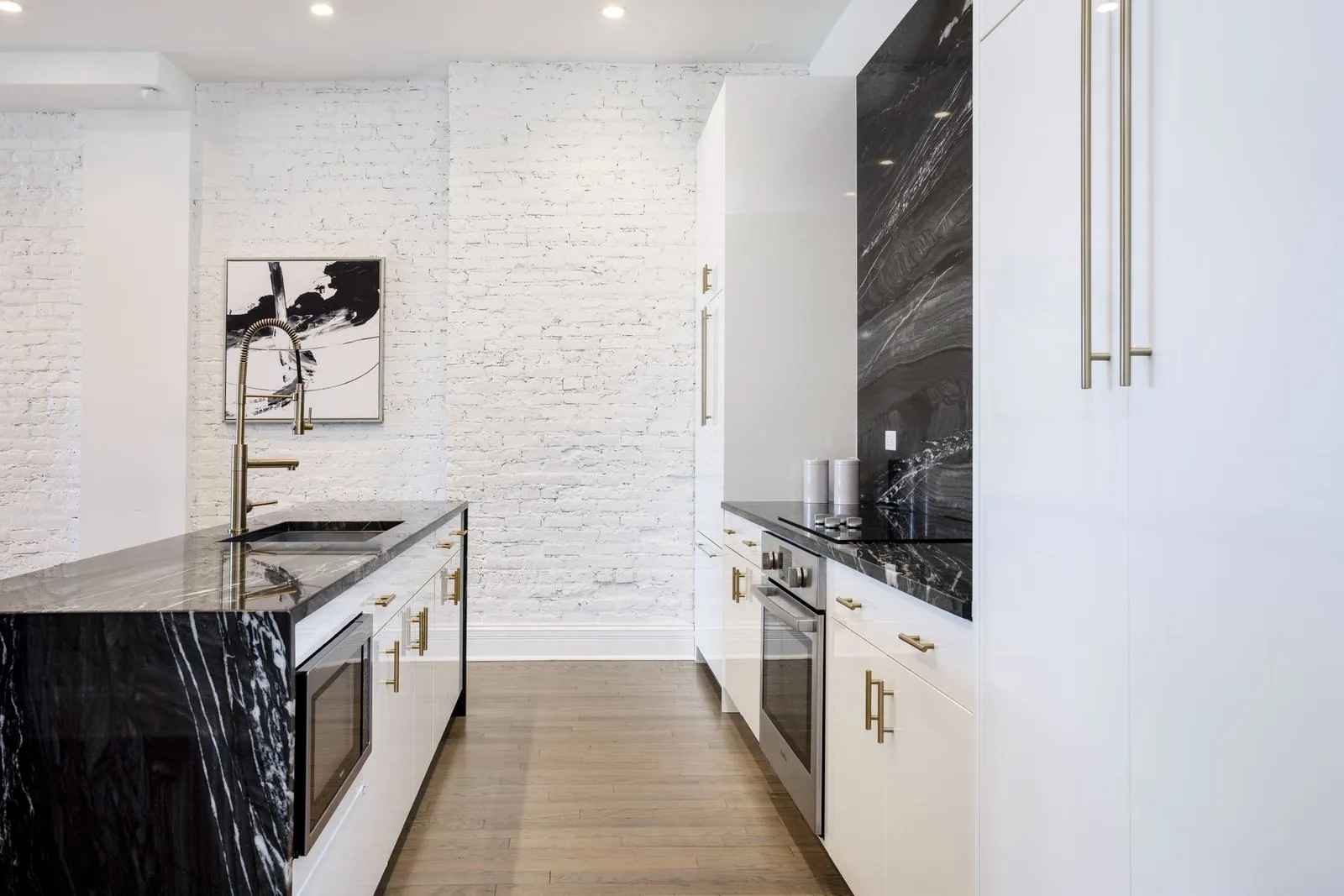 Full kitchen run with black countertops, white cabinetry, and built-in oven at 3535 Venue