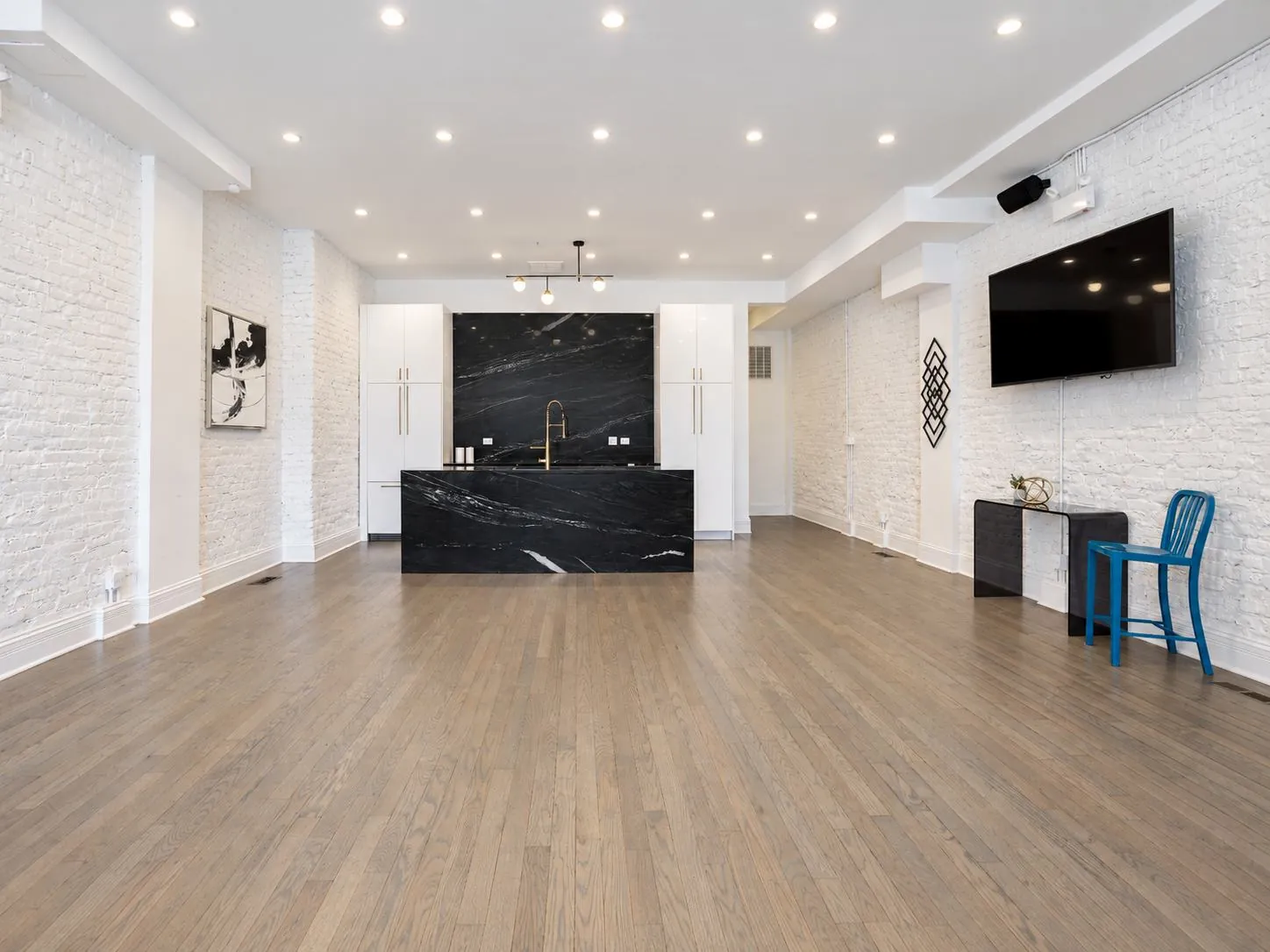 Wide view of the main event space at 3535 Venue with the black marble kitchen island, wall-mounted TV, and lounge seating