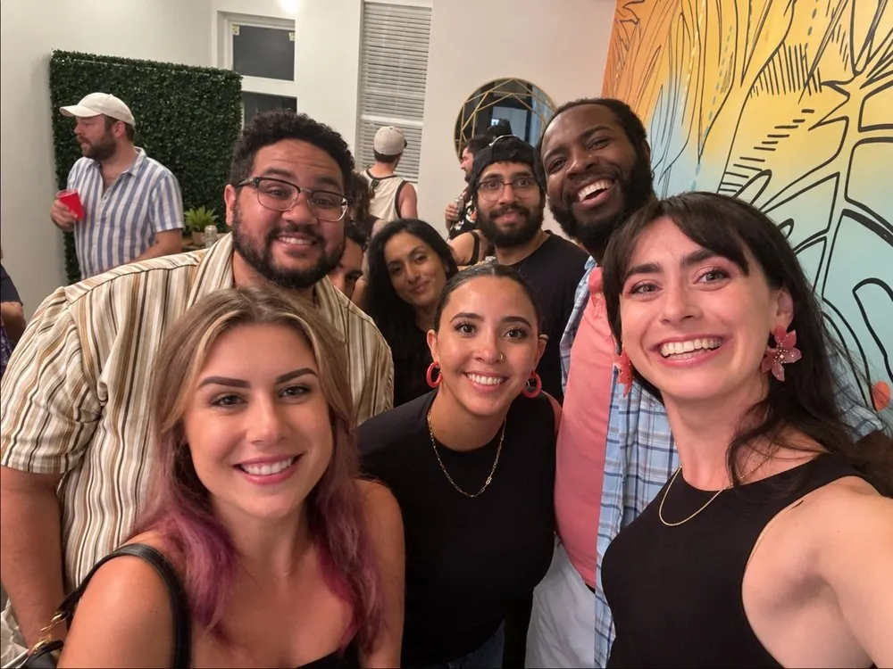 Guests taking a group selfie in front of the tropical mural
