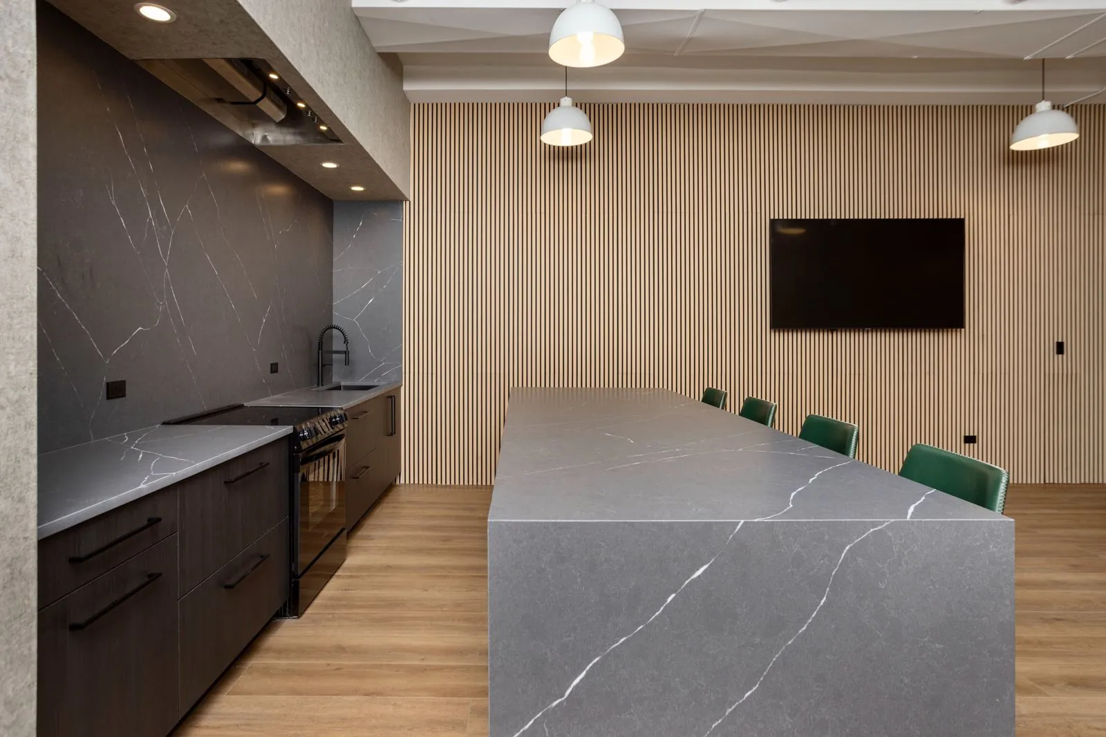 Montrose Studio full kitchen and marble island beside the wood slat wall and wall-mounted TV