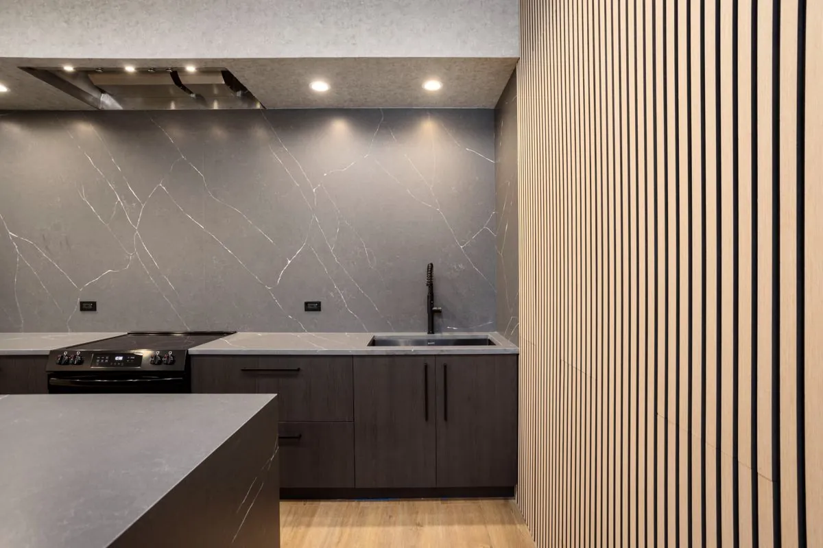 Kitchen counter, range, and sink next to the wood slat wall
