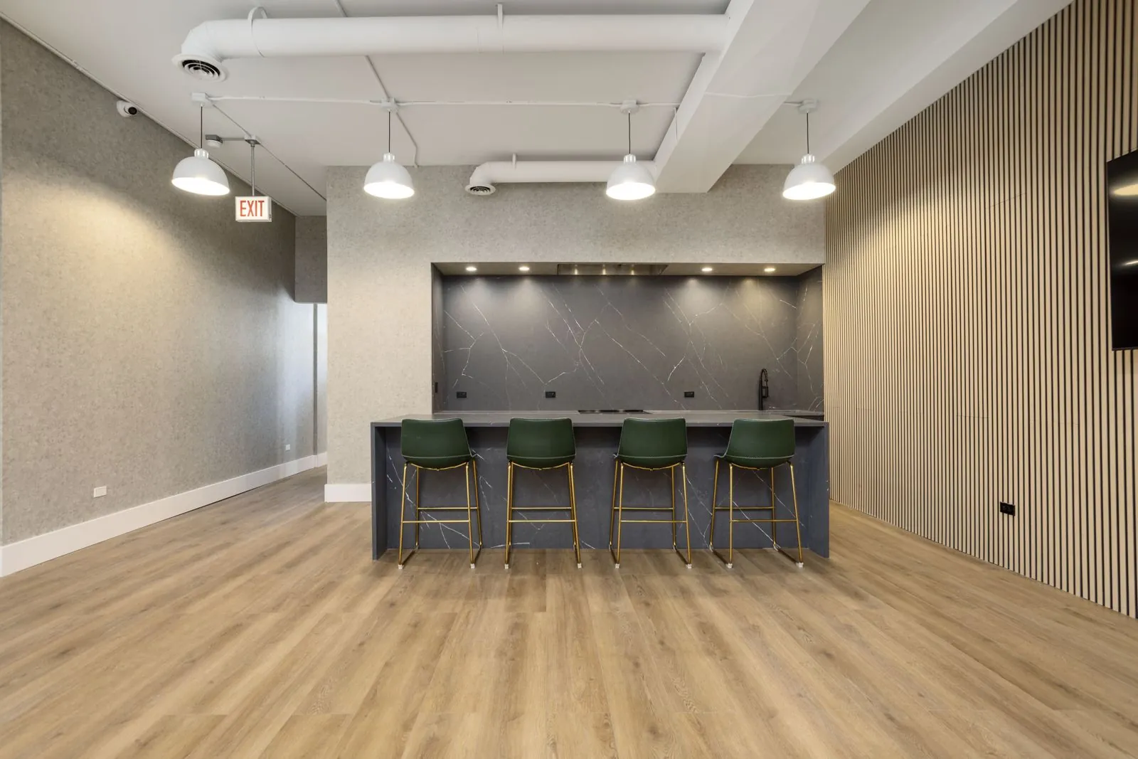 Montrose Studio kitchen island with four green bar stools in front of a gray marble backsplash