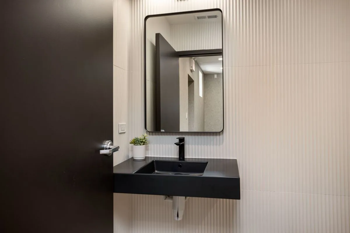 Restroom with black floating sink and framed mirror
