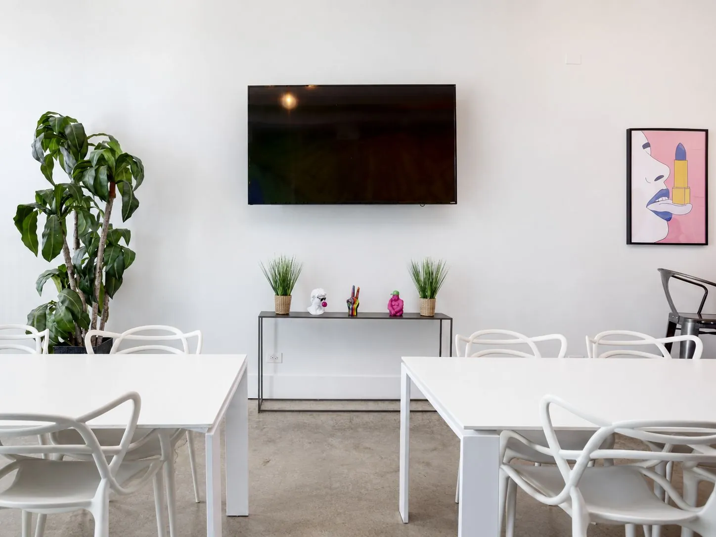 Dining tables facing the wall-mounted TV and console with plants and decor