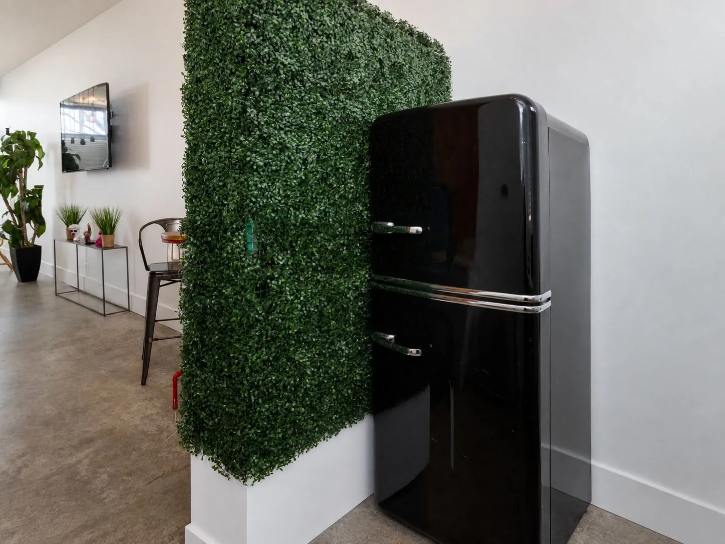 Faux-plant green wall backdrop beside the refrigerator